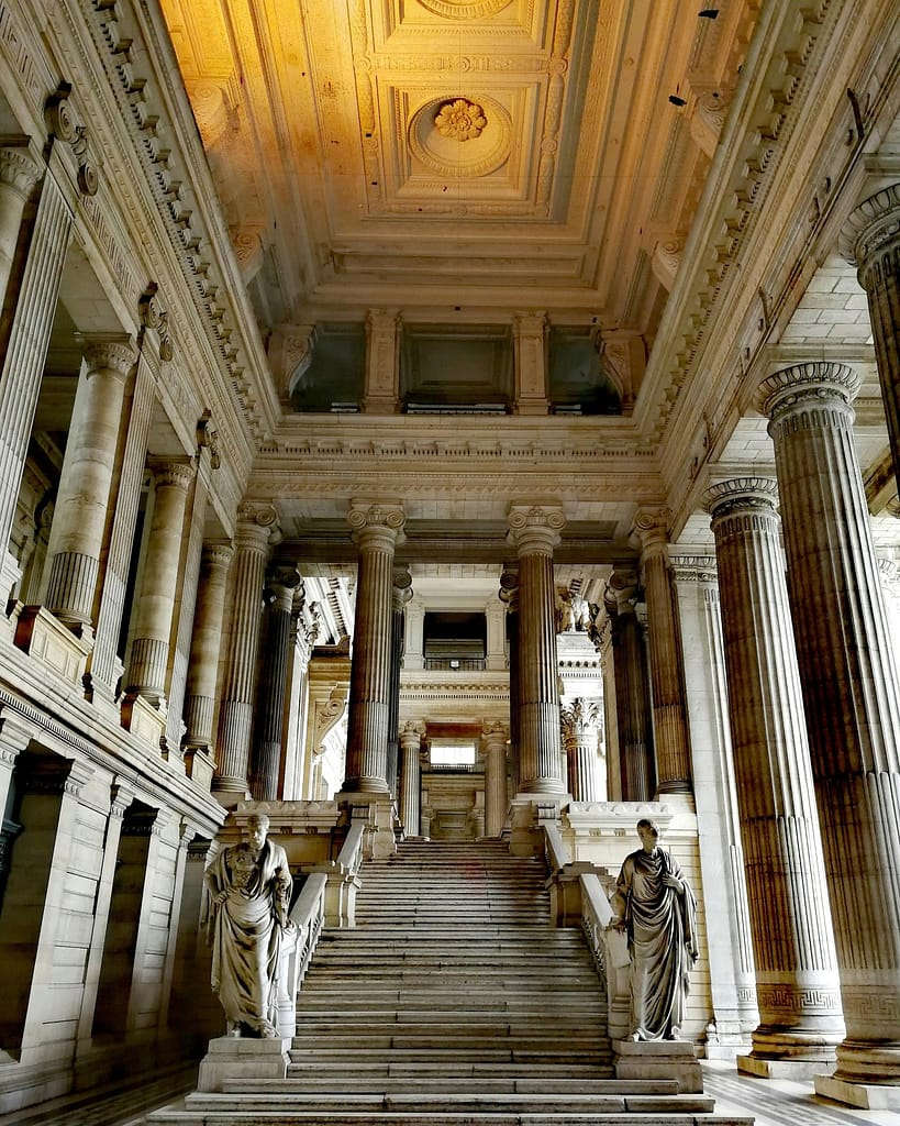 Neoclassical interior of the Law Courts of Brussels with grand columns and statues.